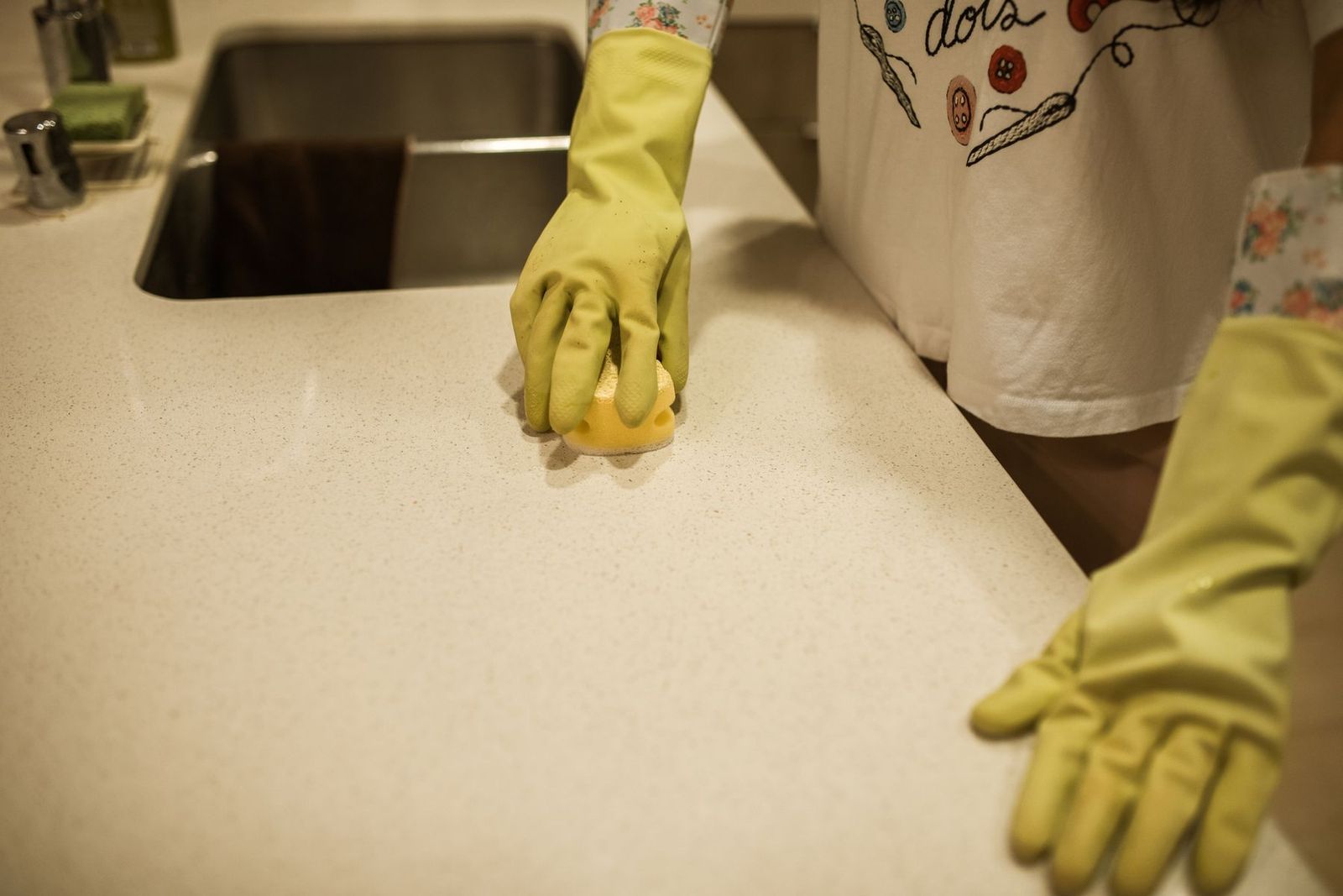 Arbeitsplatte in der Küche wird mit Handschuhen und Schwamm gereinigt