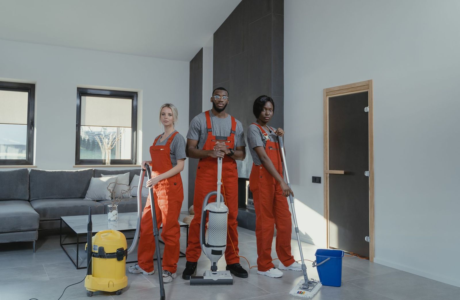 Zweierteam in roter Arbeitskleidung vor der Grundreinigung eines Wohnzimmers